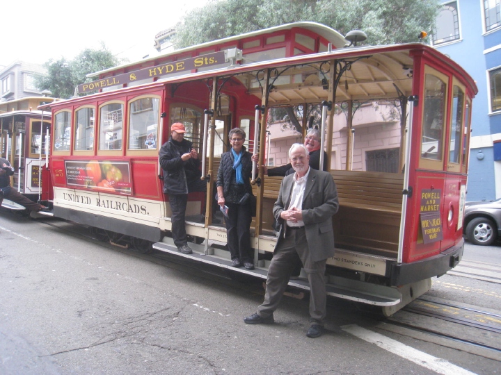 Tony Heather, Werner and Mary standing on the steps of a San Francisco cable car